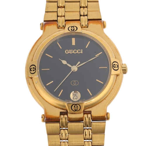 1012 - GUCCI - a gold plated 9200M quartz calendar bracelet watch, black dial with gilt baton hour markers,... 