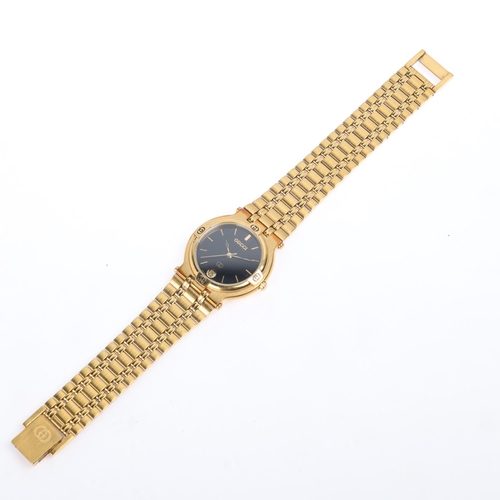 1012 - GUCCI - a gold plated 9200M quartz calendar bracelet watch, black dial with gilt baton hour markers,... 