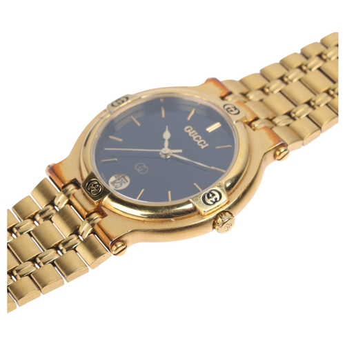 1012 - GUCCI - a gold plated 9200M quartz calendar bracelet watch, black dial with gilt baton hour markers,... 