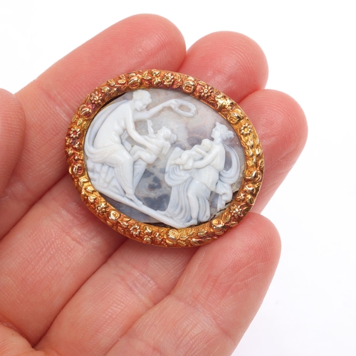 1109 - An Antique hardstone cameo brooch, the oval panel relief carved depicting female figures with cherub... 