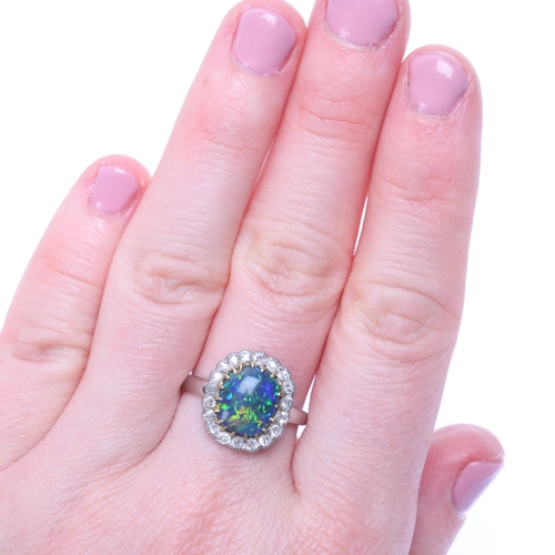 1122 - A platinum black opal and diamond cluster ring, centrally claw set with oval cabochon black opal sur... 