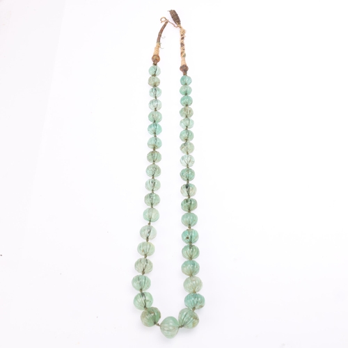 1146 - An Indian single-strand emerald bead necklace, set with a graduated row of carved and polished melon... 