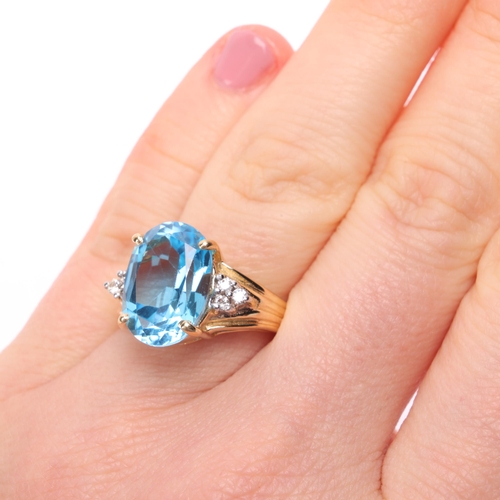 1155 - A 14ct gold blue topaz and diamond ring, claw set with oval mixed-cut topaz flanked by a trio of mod... 