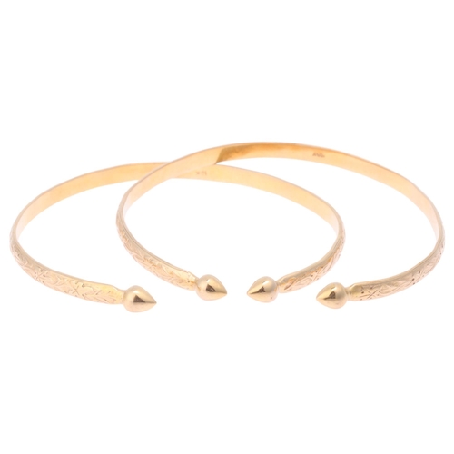 1166 - A pair of 10k gold cuff bangles, relief floral decoration with teardrop terminals, band width 4.3mm,... 