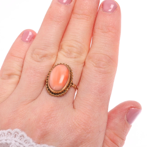 1238 - A 9ct gold coral dress ring, rub over set with oval cabochon coral within rope twist surround, setti... 