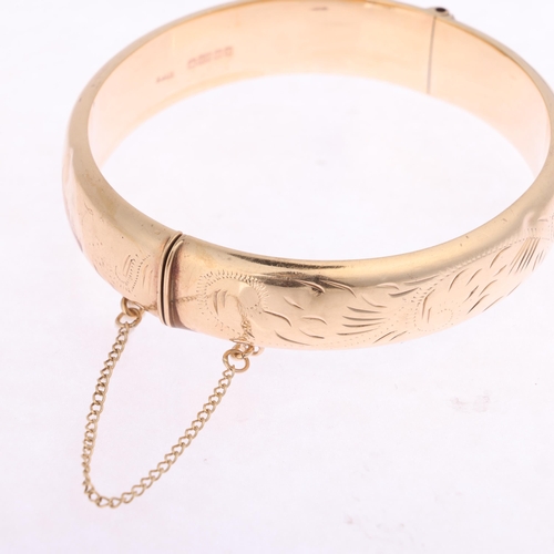 1252 - A 9ct gold hinged bangle, maker EJ Ltd, Birmingham 1984, foliate engraved decoration, band width 12.... 