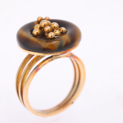 1297 - A 14ct gold modernist tigers eye ring, the polished tigers eye hoop with central organic form decora... 