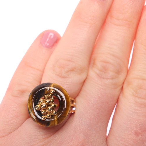 1297 - A 14ct gold modernist tigers eye ring, the polished tigers eye hoop with central organic form decora... 