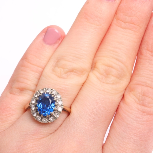 1385 - A 9ct gold paste cluster ring, London 1973, claw set with oval mixed-cut blue paste surrounded by ro... 