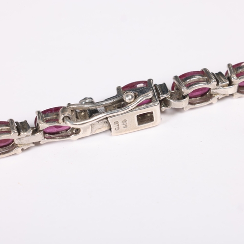 1434 - A sterling silver ruby tennis line bracelet, claw set with oval mixed-cut rubies, 20cm, 12.3g