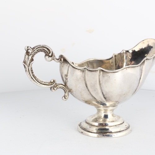 1677 - A German silver sauce boat, with scalloped rim, foliate handle and pedestal base, height 7cm, 3.5oz