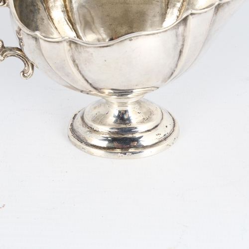 1677 - A German silver sauce boat, with scalloped rim, foliate handle and pedestal base, height 7cm, 3.5oz