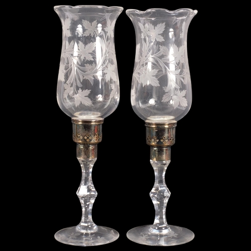 301 - A pair of engraved glass hurricane lamps with foliate designs on stands, with silver plated mounts, ... 