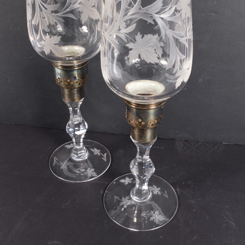 301 - A pair of engraved glass hurricane lamps with foliate designs on stands, with silver plated mounts, ... 