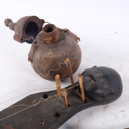 451 - A group of African Tribal items, including brass shield-shaped talisman ornament, water gourd, instr... 