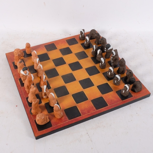 829 - An Inuit figure pottery chess set, signed Eija Seras, with leather-covered games board, 39cm across