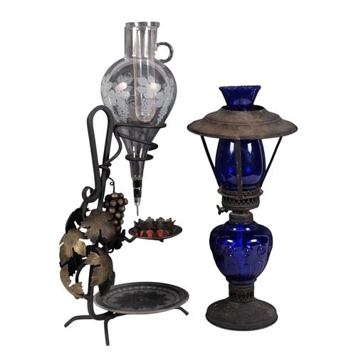 833 - A Continental wine jug, with candle holder on wrought-metal stand, H52cm, and a blue glass oil lamp