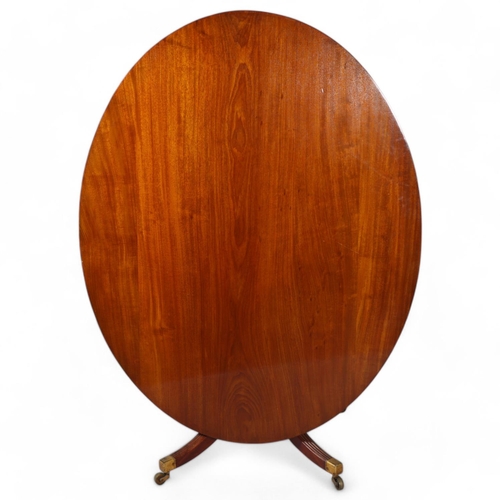 502 - A Regency oval mahogany tilt-top dining table, on quadruple base, 152cm x 119cm (5' x 3'11