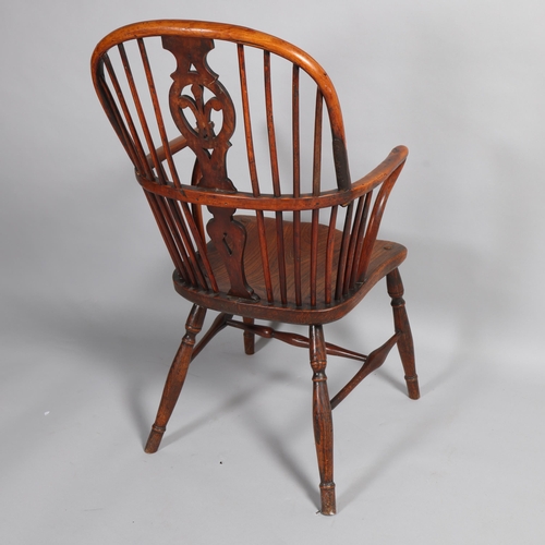 499 - An early 19th century yew wood bow arm Windsor chair, with Prince of Wales Feather design splat and ... 