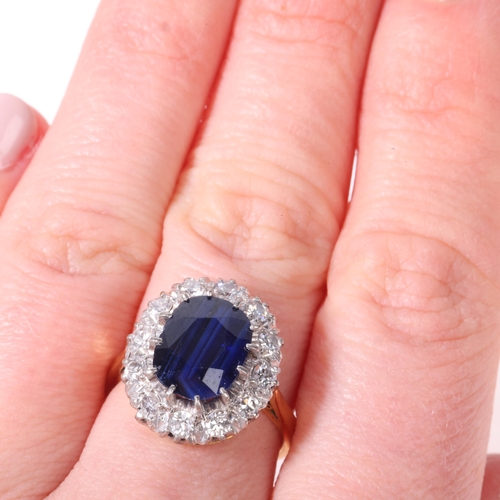 1136 - An 18ct gold sapphire and diamond cluster ring, claw set with 3.8ct oval mixed-cut sapphire surround... 