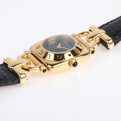 1065 - GUCCI - a lady's gold plated 6300L quartz wristwatch, blue dial with gilt leaf hands and Gucci bezel... 