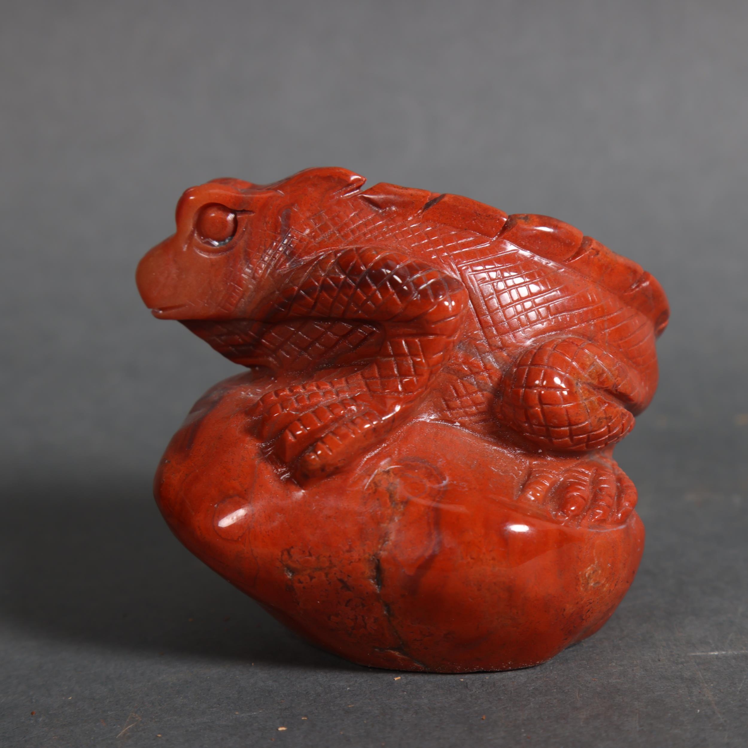 Carved Red Jasper lizard resting on rock