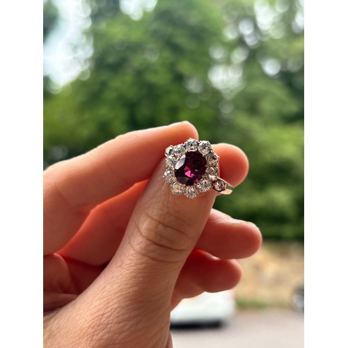 1120 - A fine 18ct gold ruby and diamond cluster ring, claw set with 2.5ct oval mixed-cut ruby surrounded b... 
