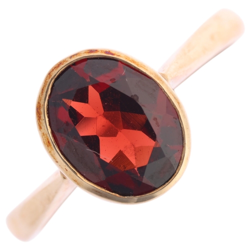1361 - A 9ct gold single stone garnet dress ring, maker BKT, Sheffield 2005, rub-over set with oval mixed-c... 