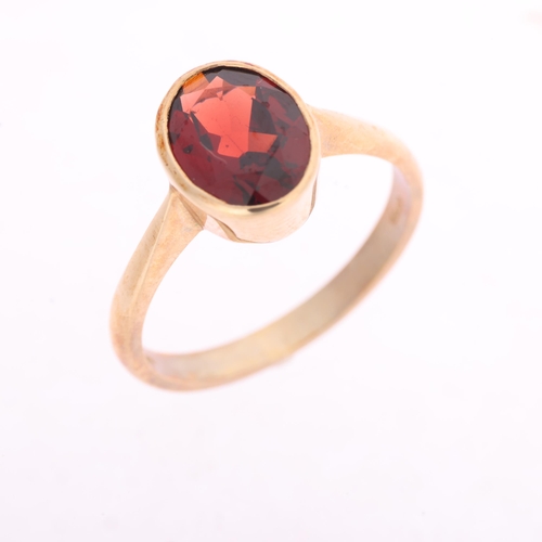 1361 - A 9ct gold single stone garnet dress ring, maker BKT, Sheffield 2005, rub-over set with oval mixed-c... 