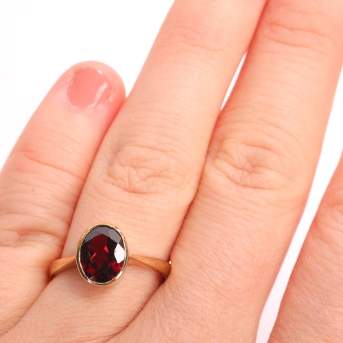 1361 - A 9ct gold single stone garnet dress ring, maker BKT, Sheffield 2005, rub-over set with oval mixed-c... 