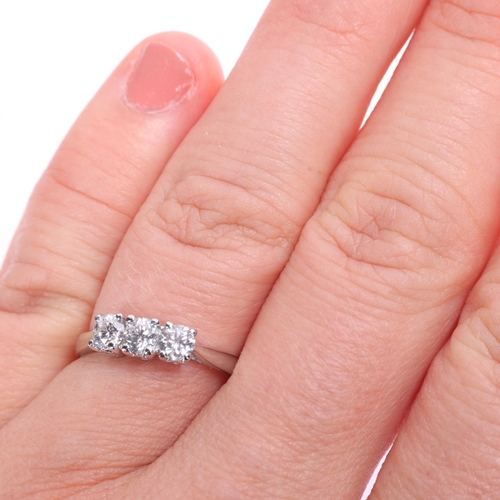 1370 - A platinum three stone diamond ring, maker JSN, claw set with modern round brilliant-cut diamonds, t... 