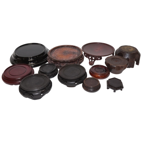 385 - A box containing 12 carved wood metal and glass Oriental stands, largest 15cm diameter