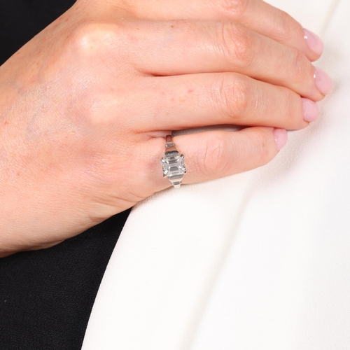 1117 - An 18ct white gold 2ct single stone emerald-cut diamond ring, maker BKT, London 1990, claw set with ... 