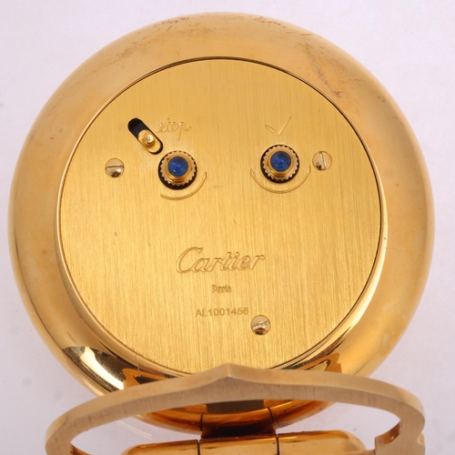 1064 - CARTIER - a gilt-metal 'Colisee' quartz alarm desk clock, round white dial with black Roman numeral ... 