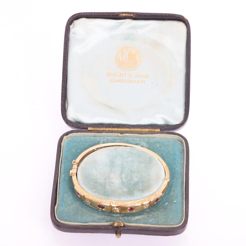 1105 - An Antique Victorian 9ct rose gold seven stone ruby and diamond hinged bangle, circa 1900, set with ... 
