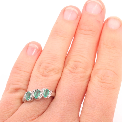 1200 - A 9ct white gold emerald and diamond half hoop ring, set with oval mixed-cut emeralds and single-cut... 