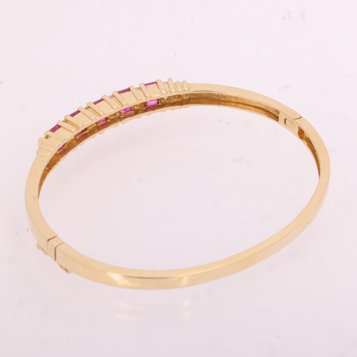 1133 - A 14ct gold ruby and diamond half hoop hinged bangle, bar set with rectangular step-cut rubies and m... 
