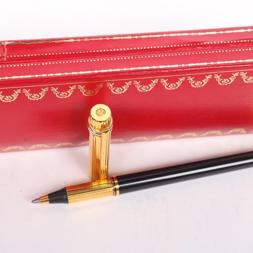 33A - Must de Cartier, A rollerball pen with black lacquer and gold plated body, in original box, length 1... 