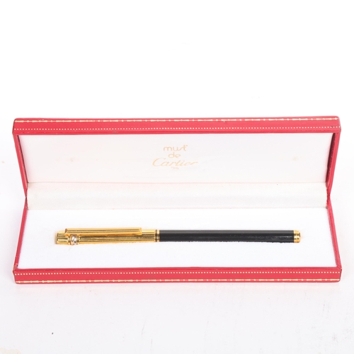 33A - Must de Cartier, A rollerball pen with black lacquer and gold plated body, in original box, length 1... 