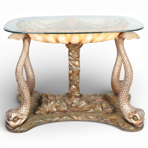 A unique mid-century Hollywood Regency polychrome carved mahogany table in the form of a seashell supported by a central column of rock like form and four fish or dolphins with glass top This table was commissioned by the former Mayor of Hove, Mr. Barry Bevan Funnell, for his wife, from his company Bevan Funnell of Newhaven in 1962. It was made by the Master Craftsman Mr. Ted Colter of the Bevan Funnell Reprodux Works in Newhaven, Sussex, height 78cm, length 108cm, depth 86cm