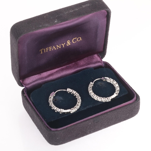 105 - TIFFANY & CO - a pair of platinum diamond hoop earrings, both set inside-out with modern round brill... 