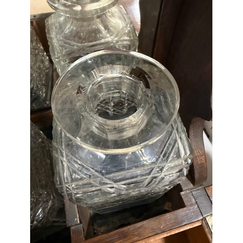 61 - A Victorian oak tantalus with 3 square cut-glass decanters, fold-out lids enclosing 3 liqueur glasse... 