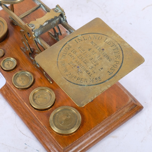 353 - A Victorian brass postal scales, on oak base, with a graduated set of weights, W26.5cm