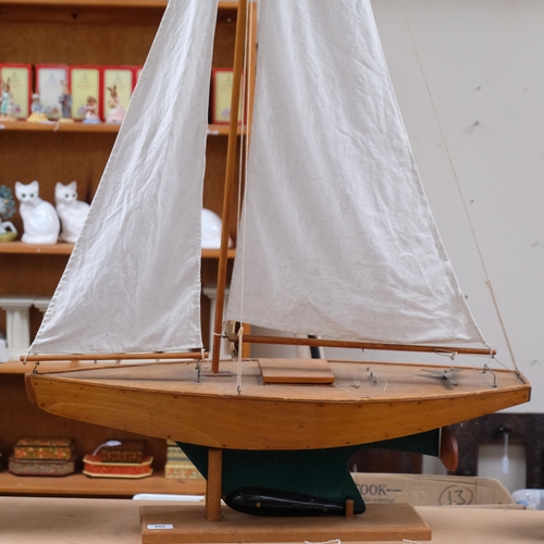 980 - A wood-hulled model pond yacht with sails, on wood stand, overall height 139cm
