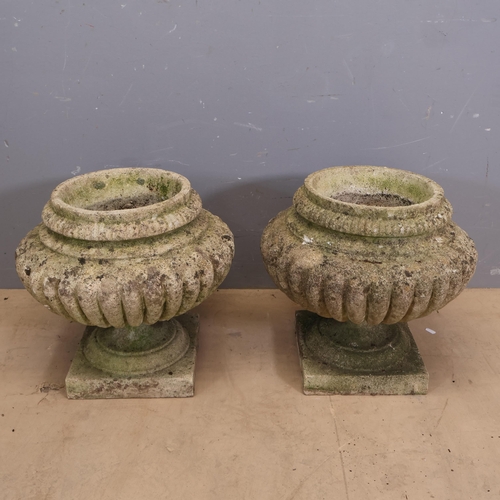 3029 - A pair of weathered reconstituted stone ovoid garden urns with excessive gadrooning on square bases.... 