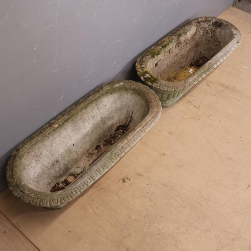 A pair of oval shaped reconstituted stone planters with neoclassical ...