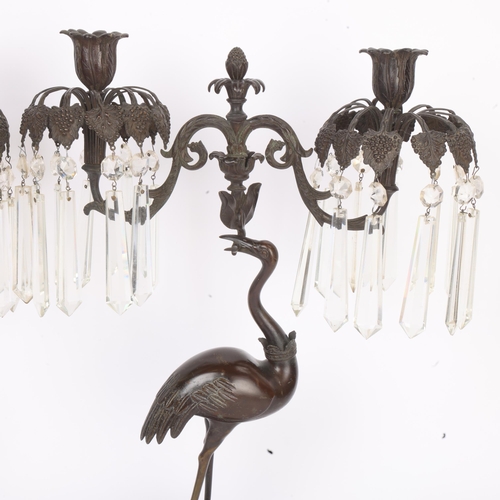 269 - A pair of Regency Period patinated bronze twin-branch candelabra, supported by cranes, with cut-glas... 