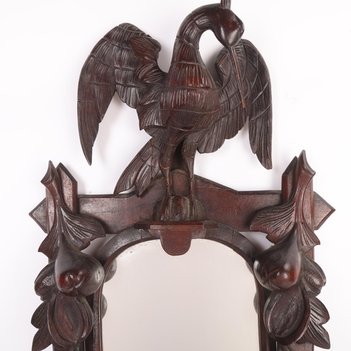 296 - A 19th century Black Forest relief carved and stained wood framed wall mirror, surmounted by a bird,... 