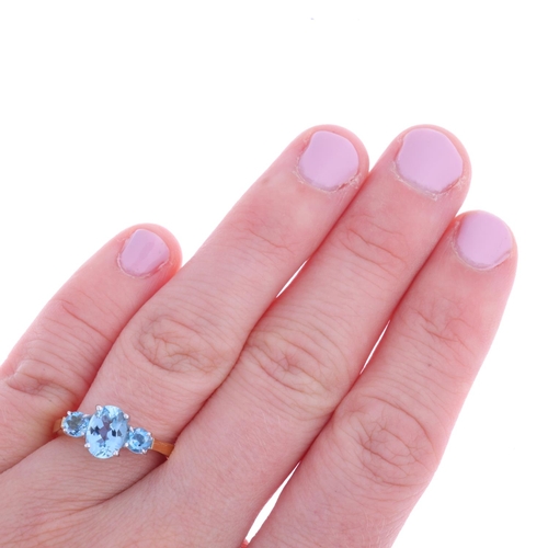 1122 - An 18ct gold three stone aquamarine ring, maker IDJC, London 1997, claw set with oval and round-cut ... 