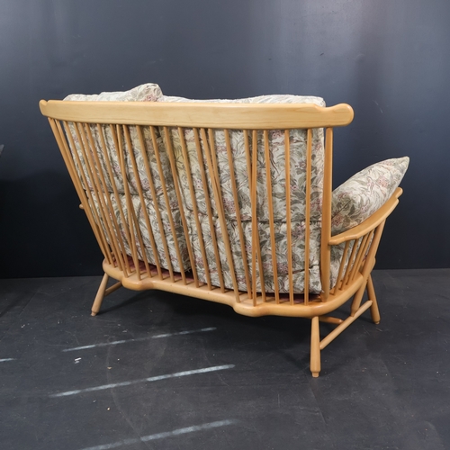 2032 - A contemporary Ercol two seater sofa in solid ash in a light finish with floral upholstered cushions... 